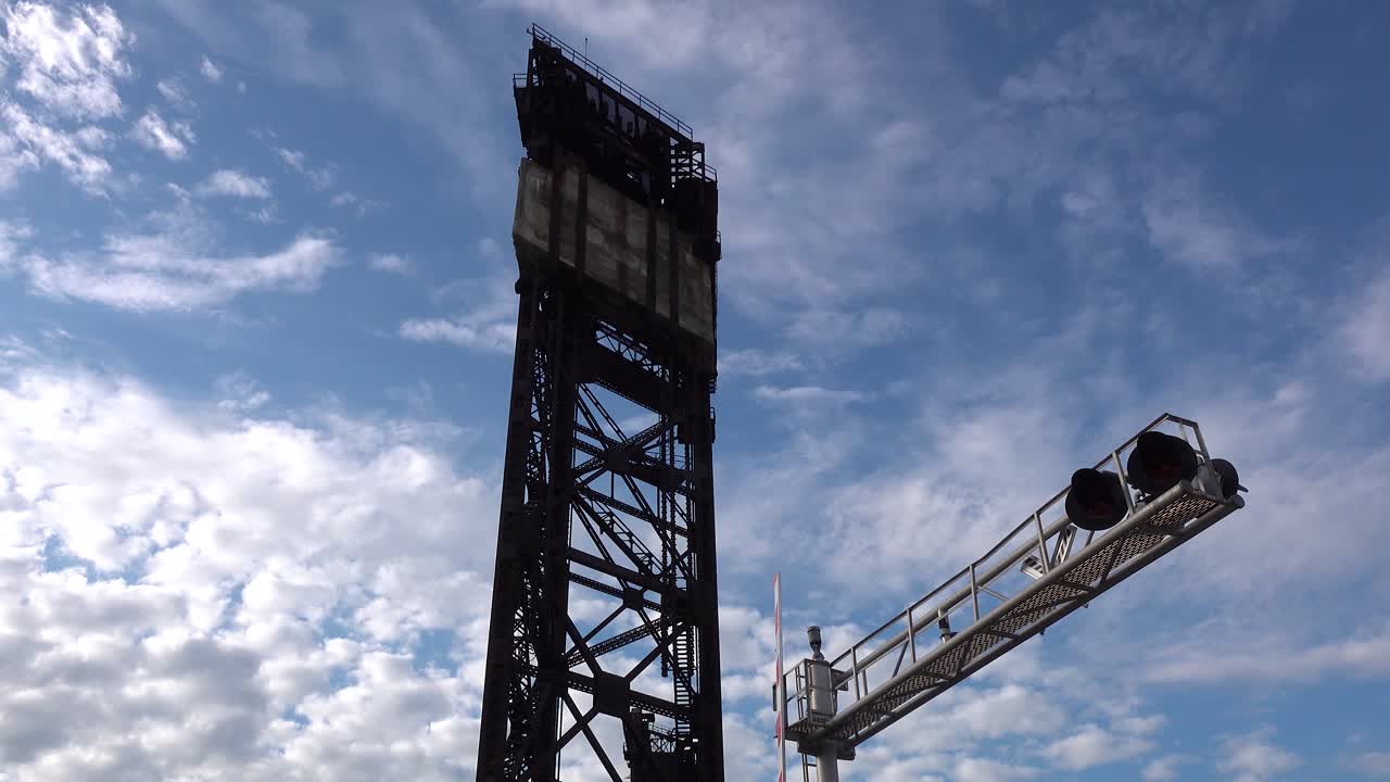 antigua torre de acero oxidado y cruce de ferrocarril timelapse con nubes blancas esponjosas y cielo azul 4k