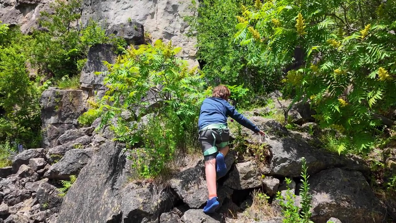 Young boy climbing up rocky cliff face at Rattlesnake Point in Milton, Ontario