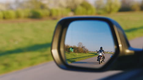 Im-Rückspiegel-Des-Fahrzeugs-Ist-Das-Motorradfahren-Von-Hinten-Zu-Sehen