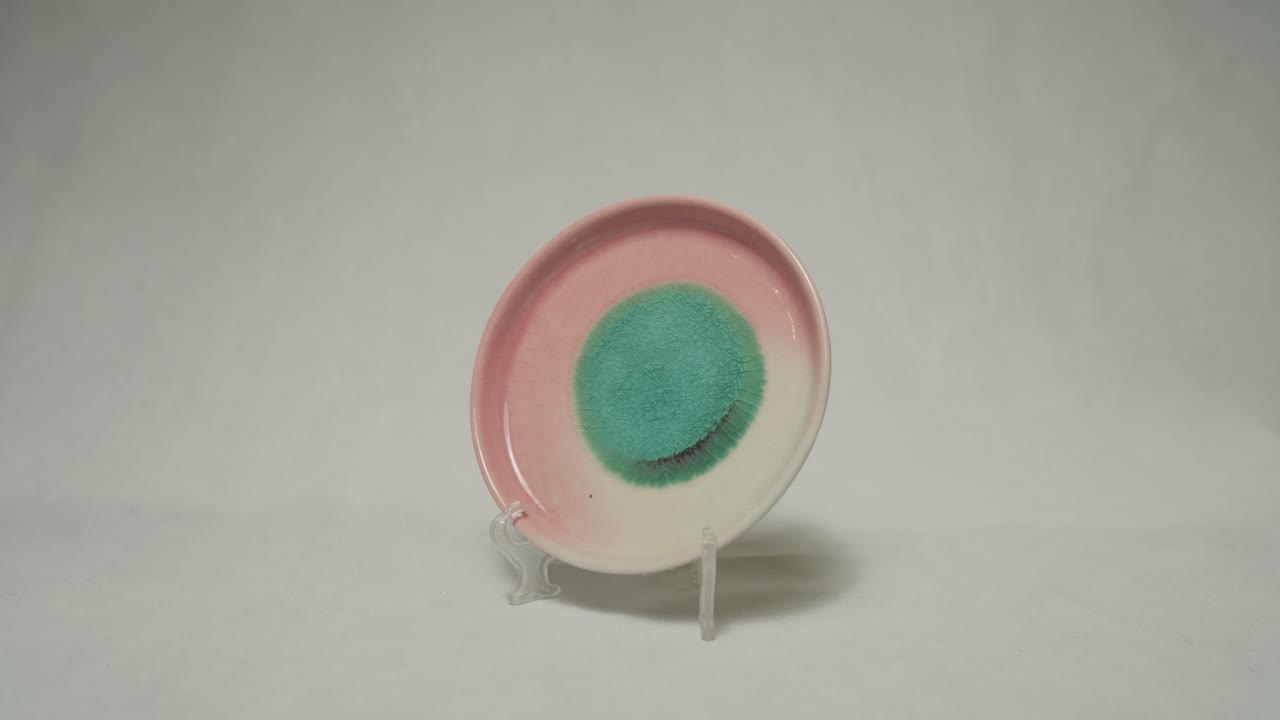 Beautiful pinkish round plate on a stand in white background.