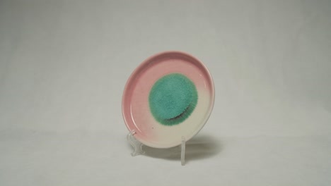 beautiful pinkish round plate on a stand in white background.
