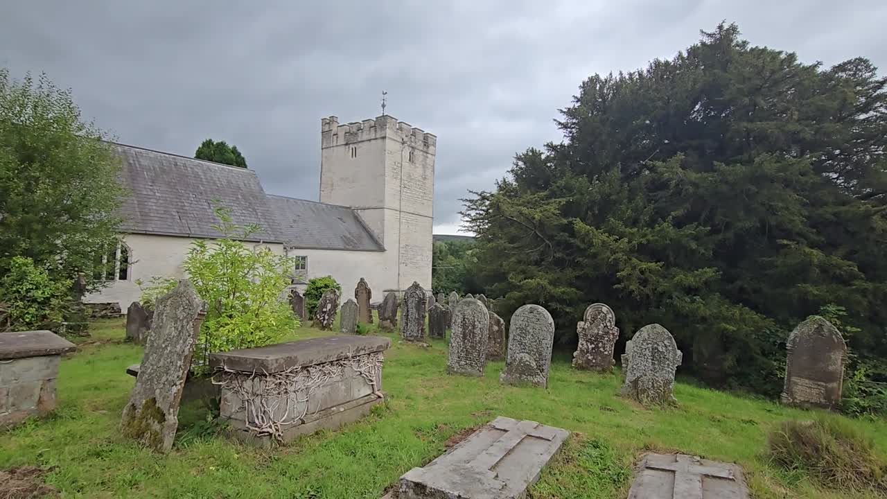 Ancient yew tree (Taxus baccata) in St. Cynog churchyard, Defynnog, near Sennybridge, Brecon, Wales, UK. Estimated 3000 years old, 11m girth. Slow pan from tree to church