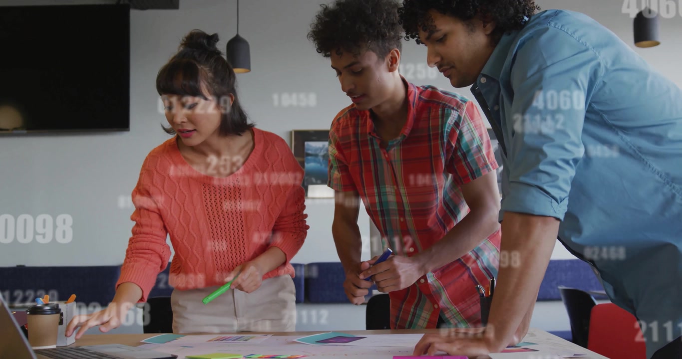 Creative team arranging markers and notes, glancing at laptop initiating design overlays