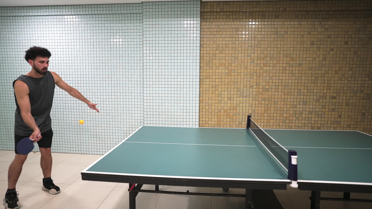 A young man makes a dynamic forehand play in a game of table tennis. This energetic shot is perfect for content about sports, recreation, and active lifestyles