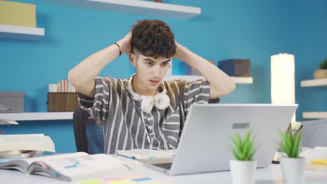 a student studying at home looks at the laptop and gets angry at what he sees.