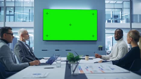 office conference room meeting using green screen chroma key tv: multi-ethnic group of top managers, executives talk. businesspeople work on an e-commerce strategy. medium wide static