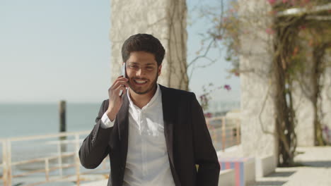 dark-haired muslim man in suit talking on phone.