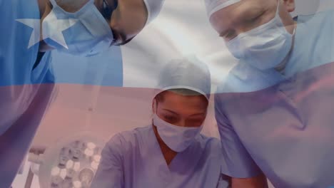 Animation-of-waving-texas-flag-against-team-of-surgeons-performing-surgery-at-hospital