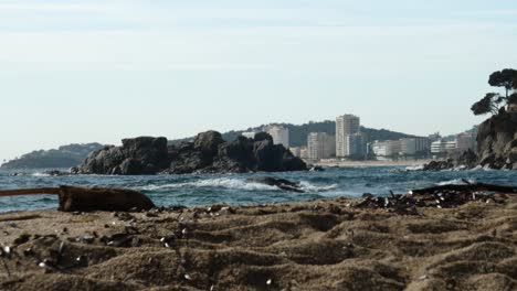 ocean waves crash against rocky shore with a coastal city in the background