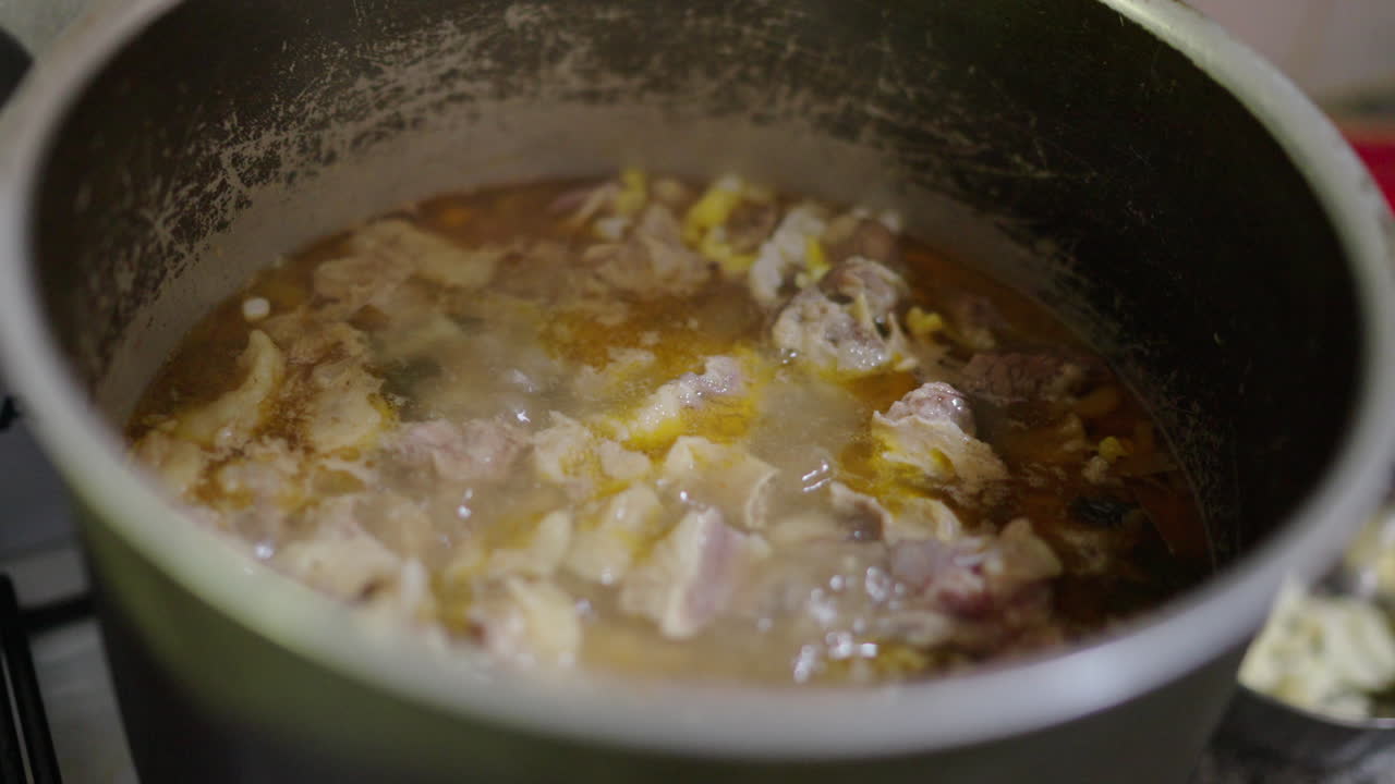 Locro stew simmers in metal pot with visible corn and beans, traditional Argentinian dish, closeup detail