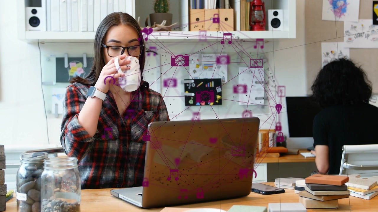 Designer al laptop che guarda, fa una pausa, digita, prende una tazza, sorseggia per concentrarsi, con sovrapposizione di rete sul laptop