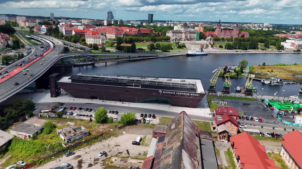 Una ripresa dall'alto che mostra il moderno edificio a forma di nave Morskie Centrum Nauki sul fiume Oder a Stettino, con architettura urbana e traffico cittadino