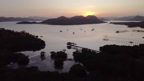 cinematic aerial footage tilting up filming the sunset with boats, the ocean and mountains in view, palawan, philippines, asia, drone