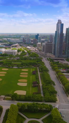 Flying over the wonderful modern park at the lake waterfront. Chicago scenery with skyscrapers at the backdrop of blue cloudy sky. Vertical video
