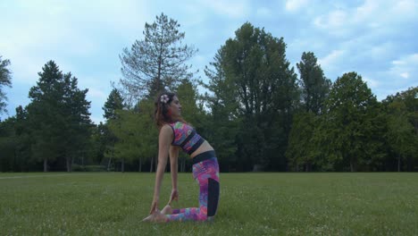 Young-Attractive-Female-Doing-Yoga-on-Grass,-Making-Camel-Position-and-Namaste-Sign,-Slow-Motion