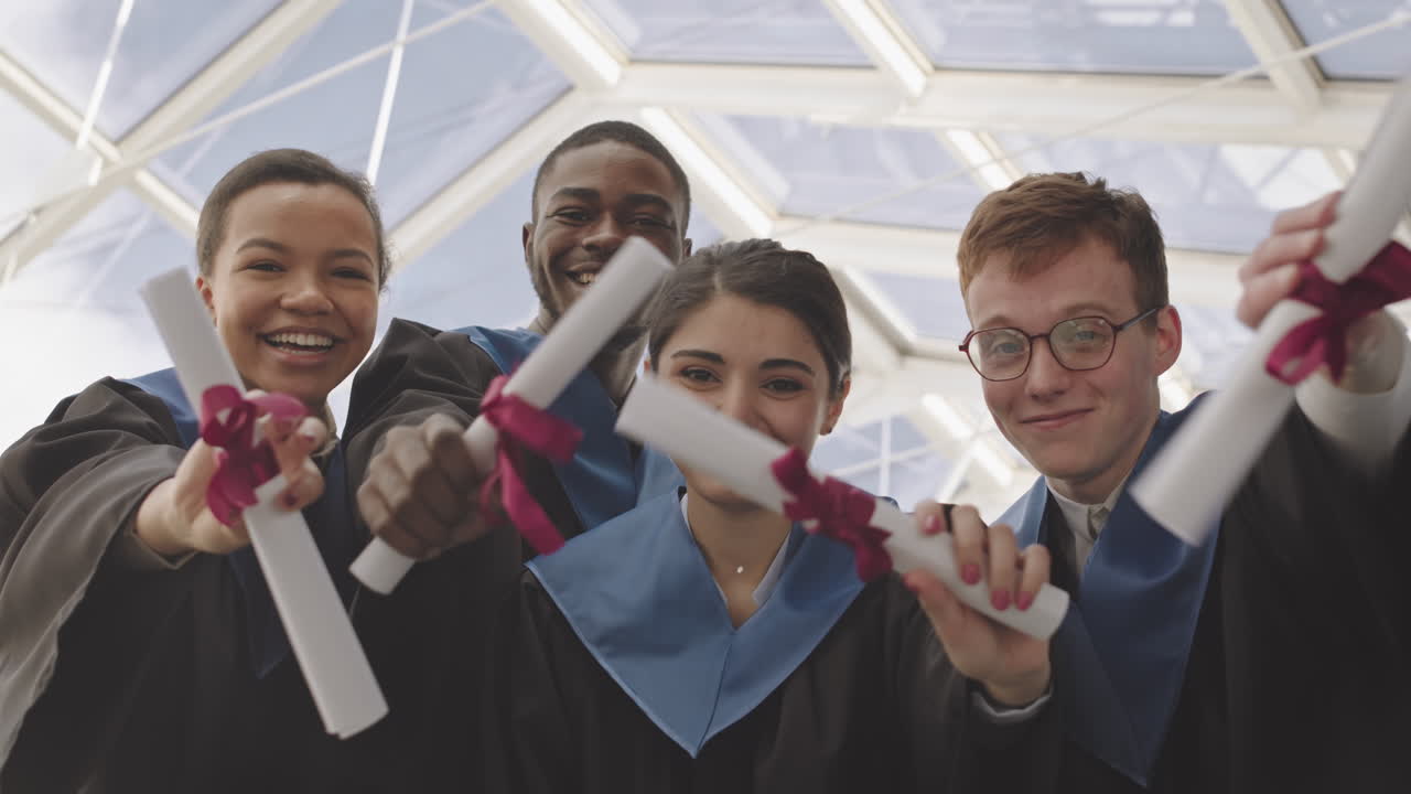 Four Diverse Cheerful Graduates Looking at Camera