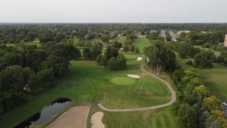 Carritos-De-Golf-Estacionados-Cerca-De-árboles-En-Un-Vasto-Campo,-Vista-Aérea-De-Drones,-Campo-De-Golf-Plum-Brook-En-Sterling-Heights-Michigan