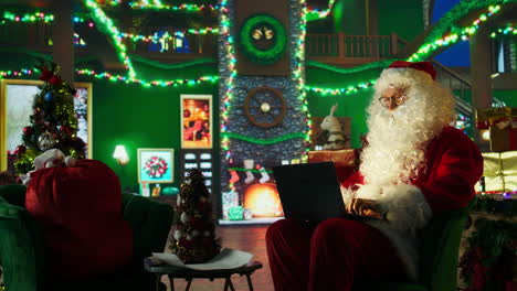 santa claus working on a laptop in a cozy christmas setting