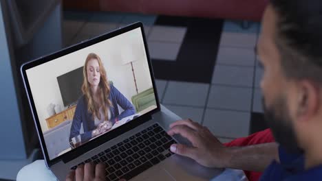 middle eastern man having a video call with female colleague on laptop