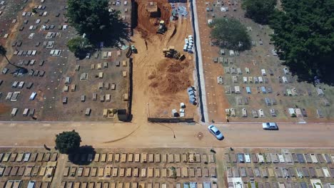 tractors and workers building new tombs to receive coronavirus victims, in brasilia cemetery