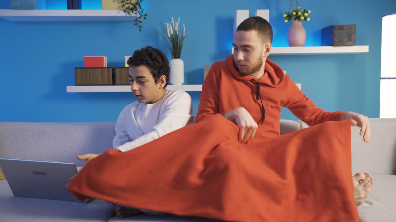 남동생과 남동생이 집에서 늦은 밤에 노트북에서 영화를 보고 있습니다.