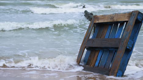 vieja paleta de epal de madera azul en la orilla, basura y basura en una playa vacía de arena blanca del mar báltico, problema de contaminación ambiental, día nublado, plano medio