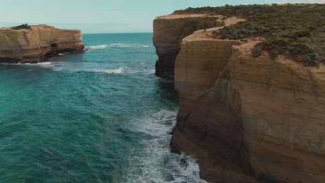 4k aerial high coastal cliff with blue ocean drone dolly in + tilt down shot