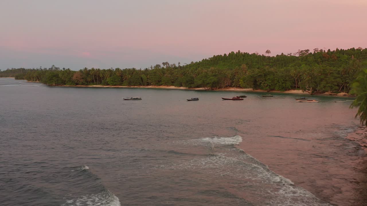 Drone revealing a small bay with boats and resorts on a small tropical island in Northern Mentawai