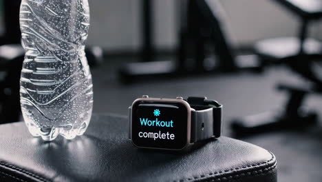 workout complete - fitness tracker and water bottle in gym
