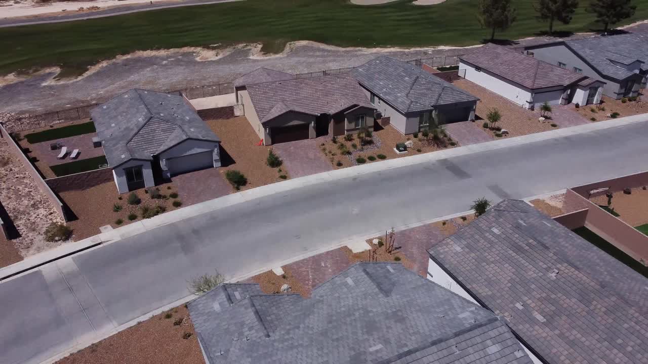 Drone sobre carro trafegando por um bairro suburbano desértico.