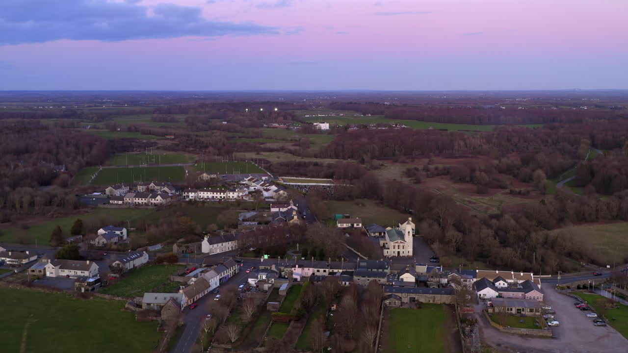 Overhead descend establishing of Clarinbridge during golden hour with sun low on the horizon over fields, blue hour dusk. Ireland