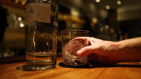 hand pouring whiskey into a glass over ice