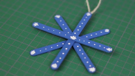 blue snowflake made of popsicle sticks on a cutting mat