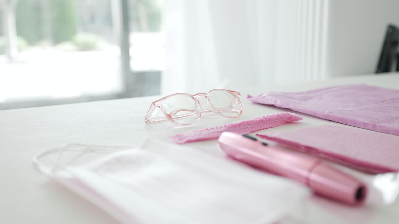 Pink Safety Glasses laying on a brightly lit bed along side other sanitary equipment