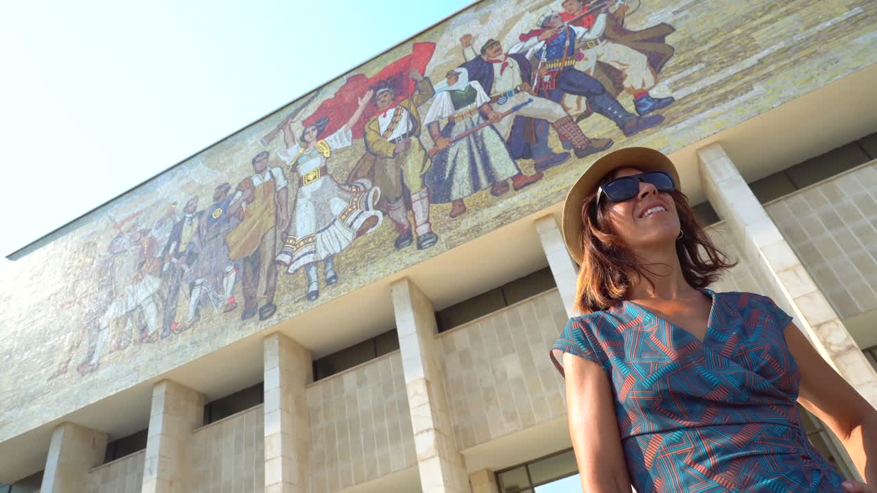 Mujer delante de un edificio con un mosaico