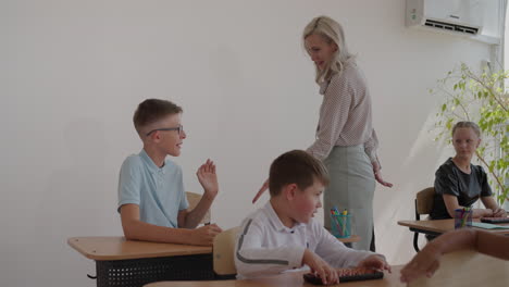 the teacher high-fives the boy in the classroom during the lesson