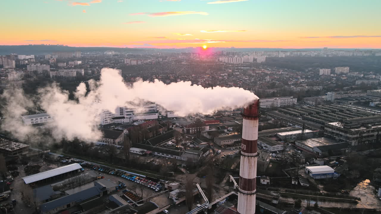 Aerial drone view of Chisinau at sunset. Tube of the thermal station with smoke coming out. Industrial zone near it and cityscape on the background. Moldova