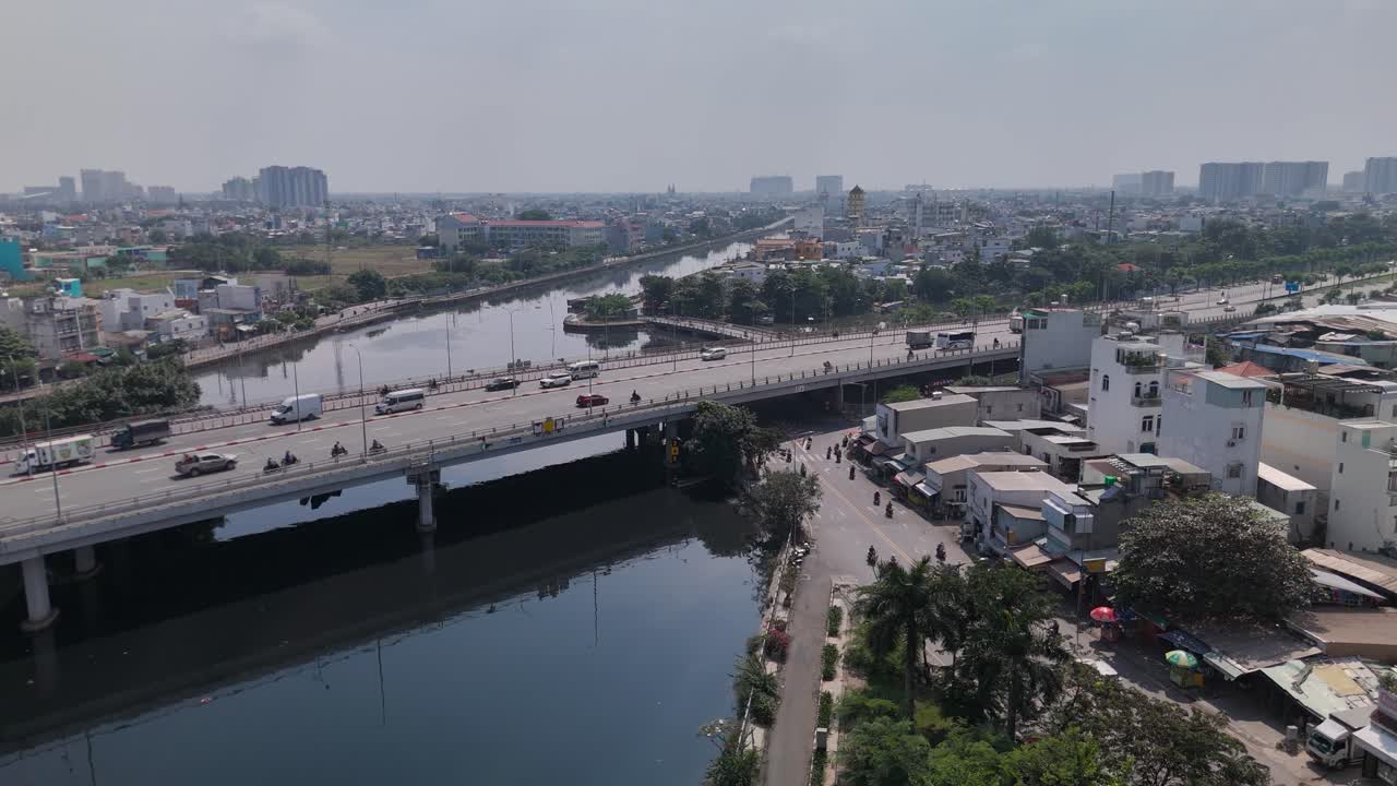 Aerial view of busy freeway over river with urban sprawl on sunny clear day at medium altitude