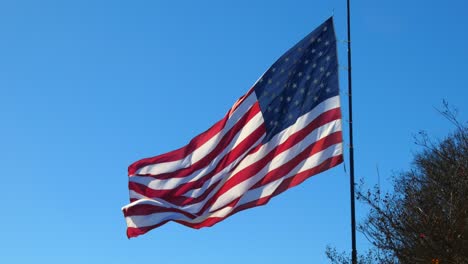 the stars and stipes of the real american flag blowing in the wind against a blue sky