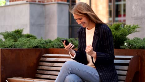 business woman celebrating success while using smartphone