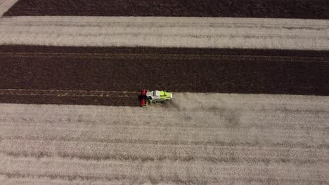 imágenes de drones de arriba hacia abajo de un campo de frijoles de alimentación oscuros que está siendo cosechado por una cosechadora