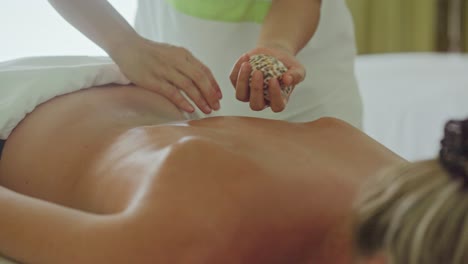 Hot cowrie sea shell relaxing back rub on caucasian woman&#039;s, Maldives
