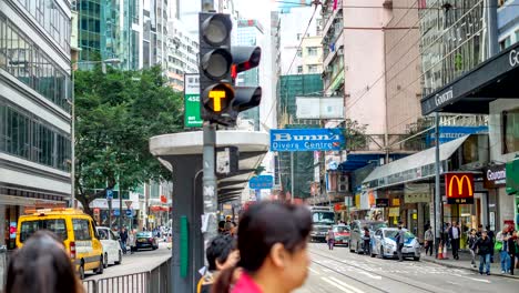 4k timelapse of downtown hong kong with people wait railroad track at tram station. people walking cross the road