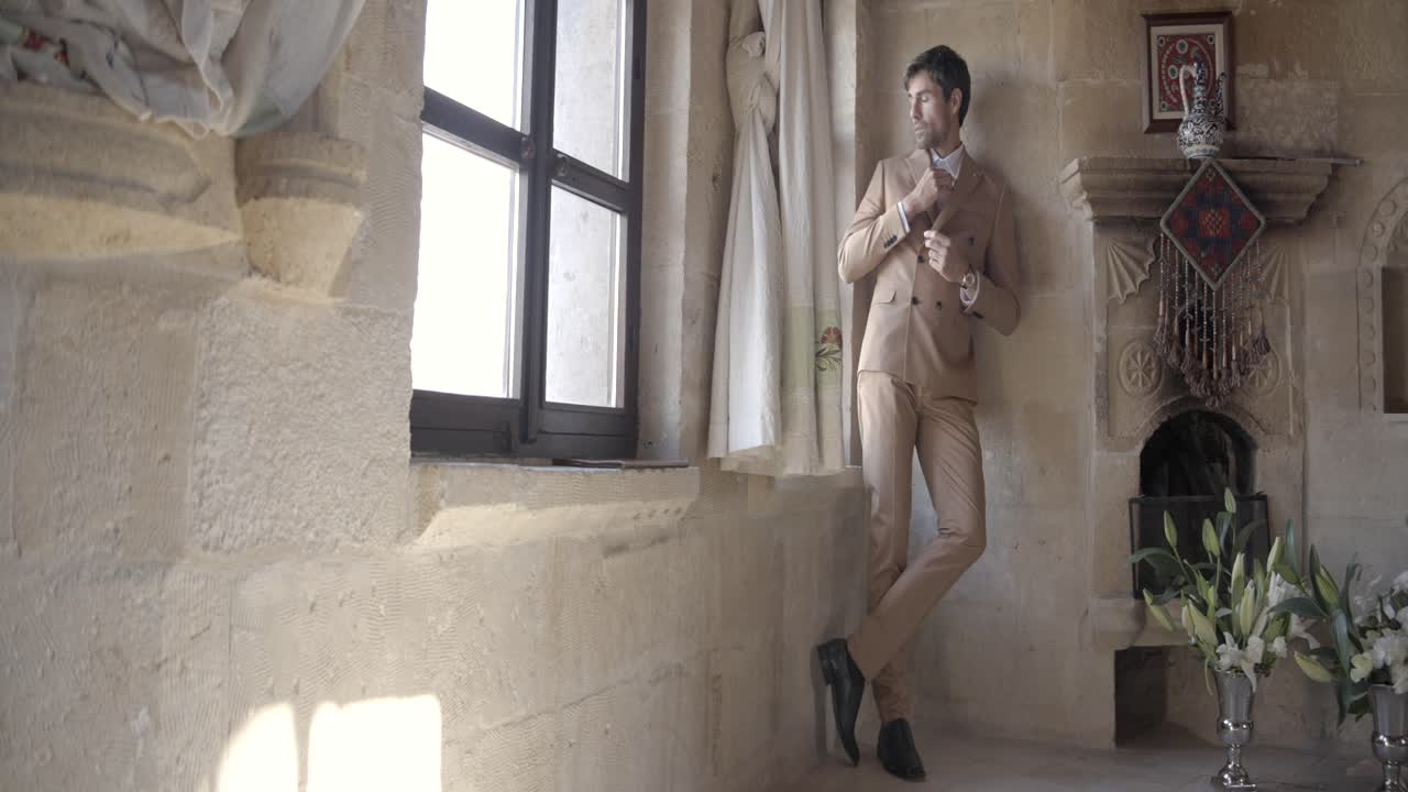 hombre de traje junto a una ventana en una casa vieja