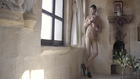 man in a suit by a window in an old house