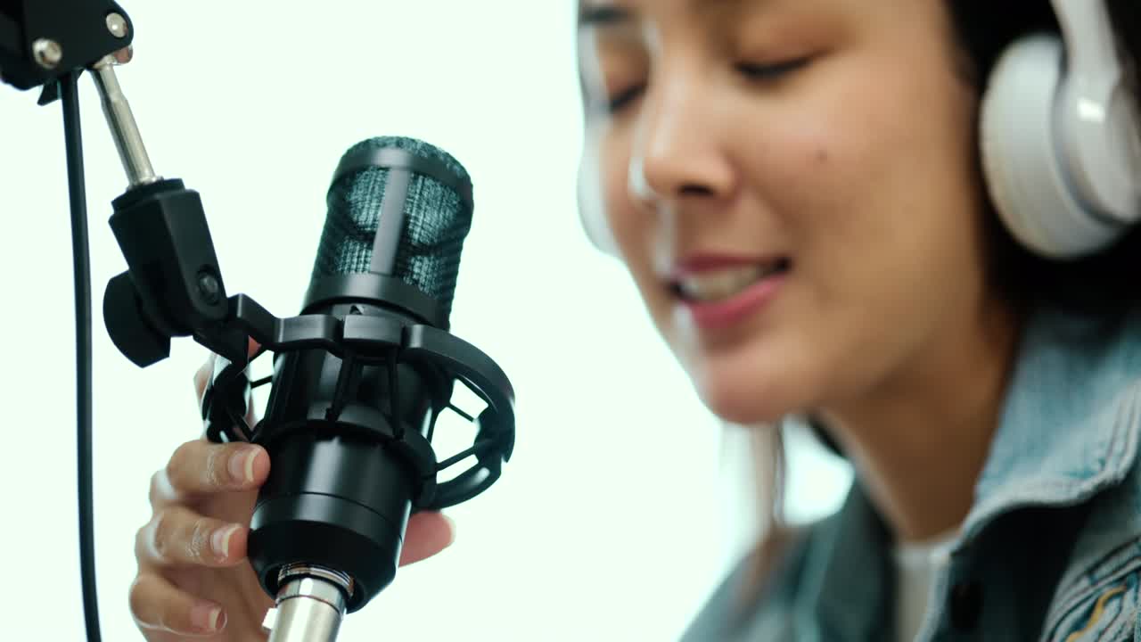 Close-up condenser microphone of content creator woman host streaming his a podcast on laptop with headphones interview conversation at home broadcast studio. Blogger recording voice over radio.