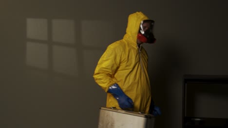 hombre vestido con traje de materiales peligrosos explora una habitación llena de humo