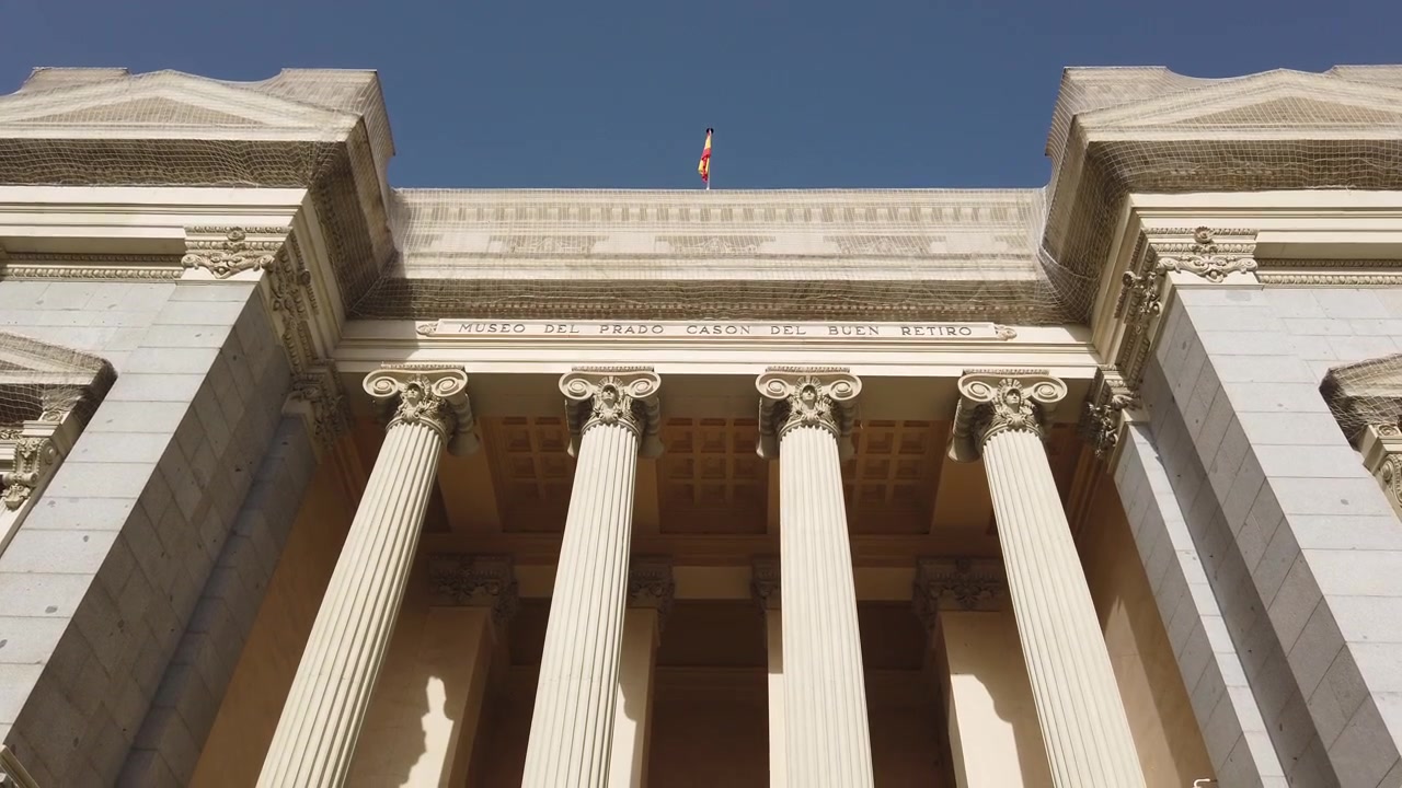 Inquadratura dal basso con tilt verso il basso delle colonne neoclassiche del Casón del Buen Retiro e della bandiera spagnola, Madrid Spagna