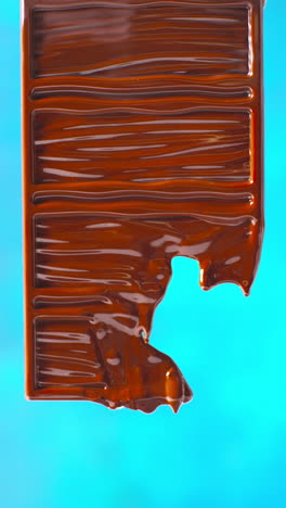 video vertical de primer plano de una barra de chocolate derretida contra un fondo de color azul con espacio de copia 2