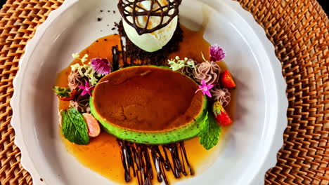 an exquisitely plated gourmet dessert featuring a pandan crème brûlée with caramel, a scoop of vanilla ice cream in a chocolate cage, and decorated with edible flowers at kuta selatan bali